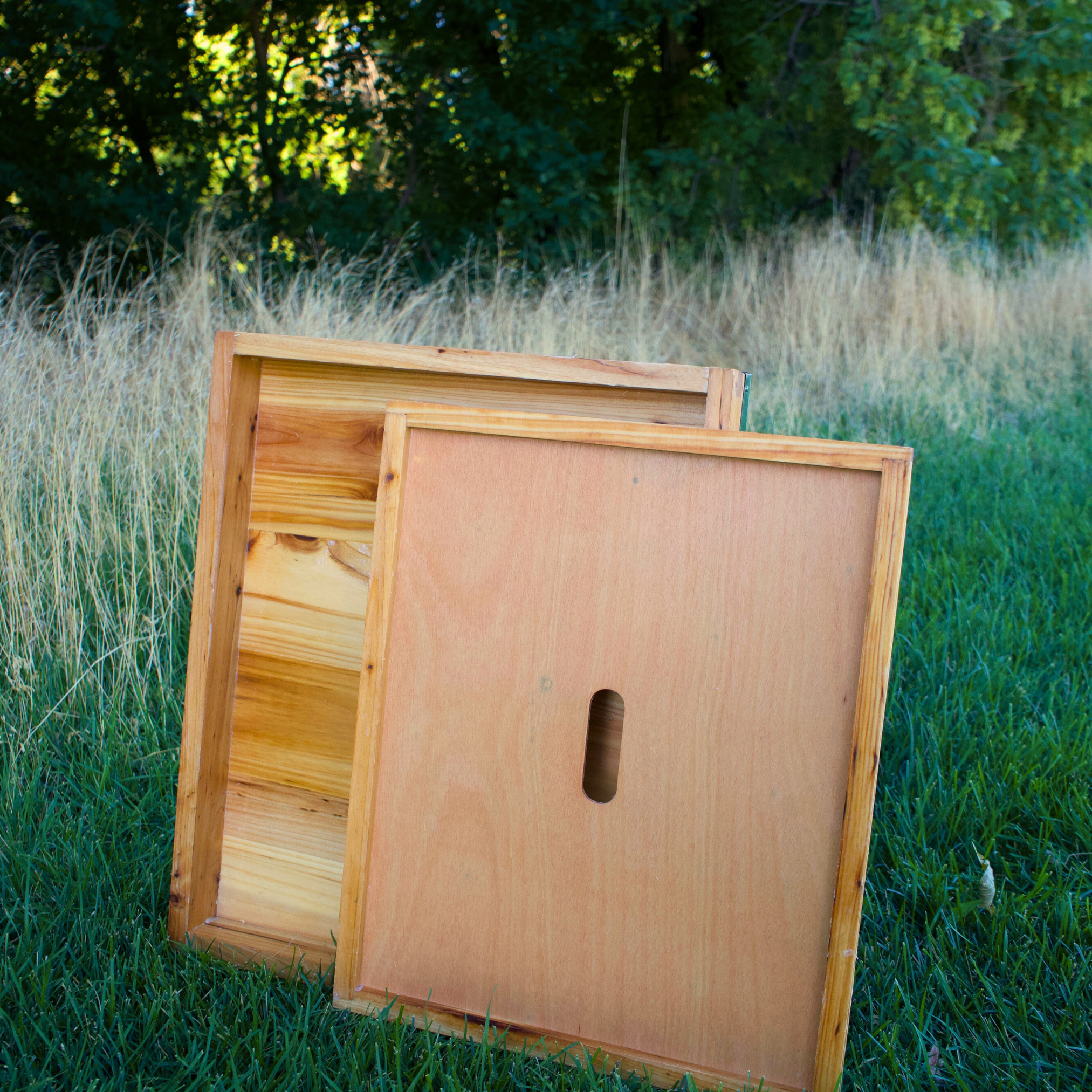 Beehive lid and inner cover are displayed in a green grass field. Both components are made from premium pine and are double wax dipped.