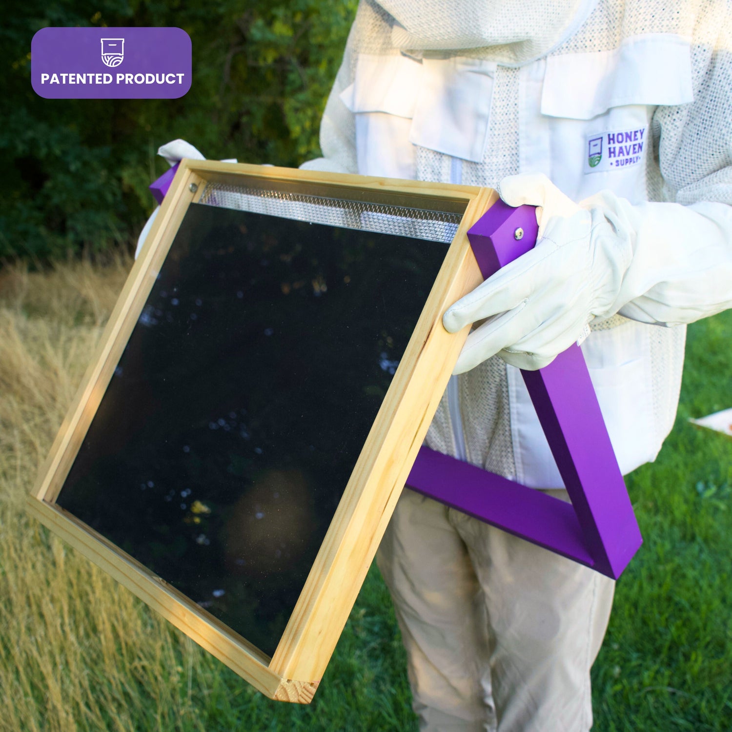 Man in white mesh ventilated beekeeping jacket holding a HiveHeater, a watermark explains that the product is patented!