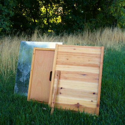 A beehive lid, inner cover, bottom board, and entrance reducer are all displayed in a green grass field. All these components are made from high quality pine and are double wax dipped!